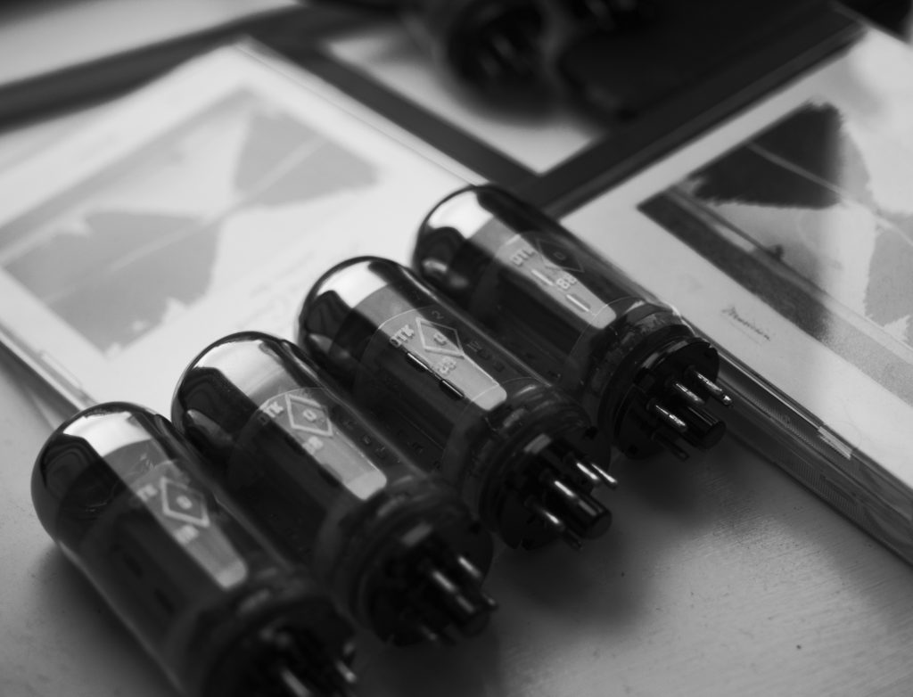 Four Russian 6P3S-E (6П3С-Е) output tubes lying next to three different CD editions of Bill Evans's 'The Paris Concert, Edition Two'.